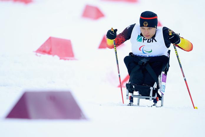 A female sit-skiing athlete is competing 